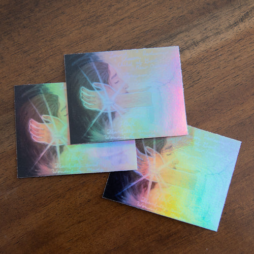 3 stickers with artistic designs of hands and feet on a wooden surface